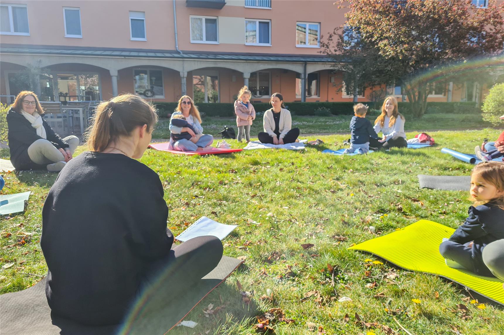 Kinder und Eltern gemeinsam auf Yoga-Matten im Innenhof des Klostergarten Kevelaer