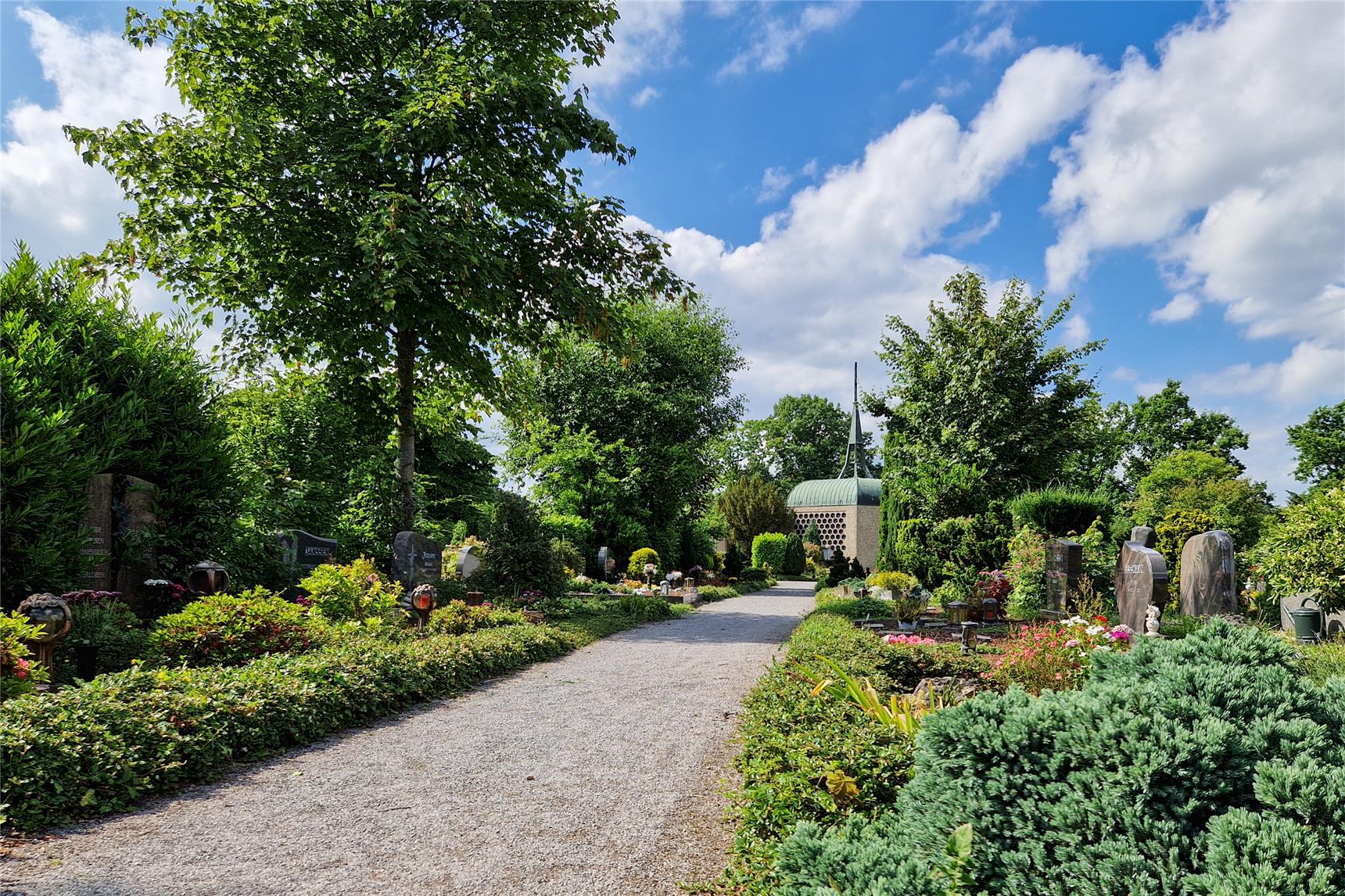 Blick auf eine Gräberreihe auf dem Friedhof von Kevelaer. Im Hintergrund ist die Friedhofshalle zu sehen.