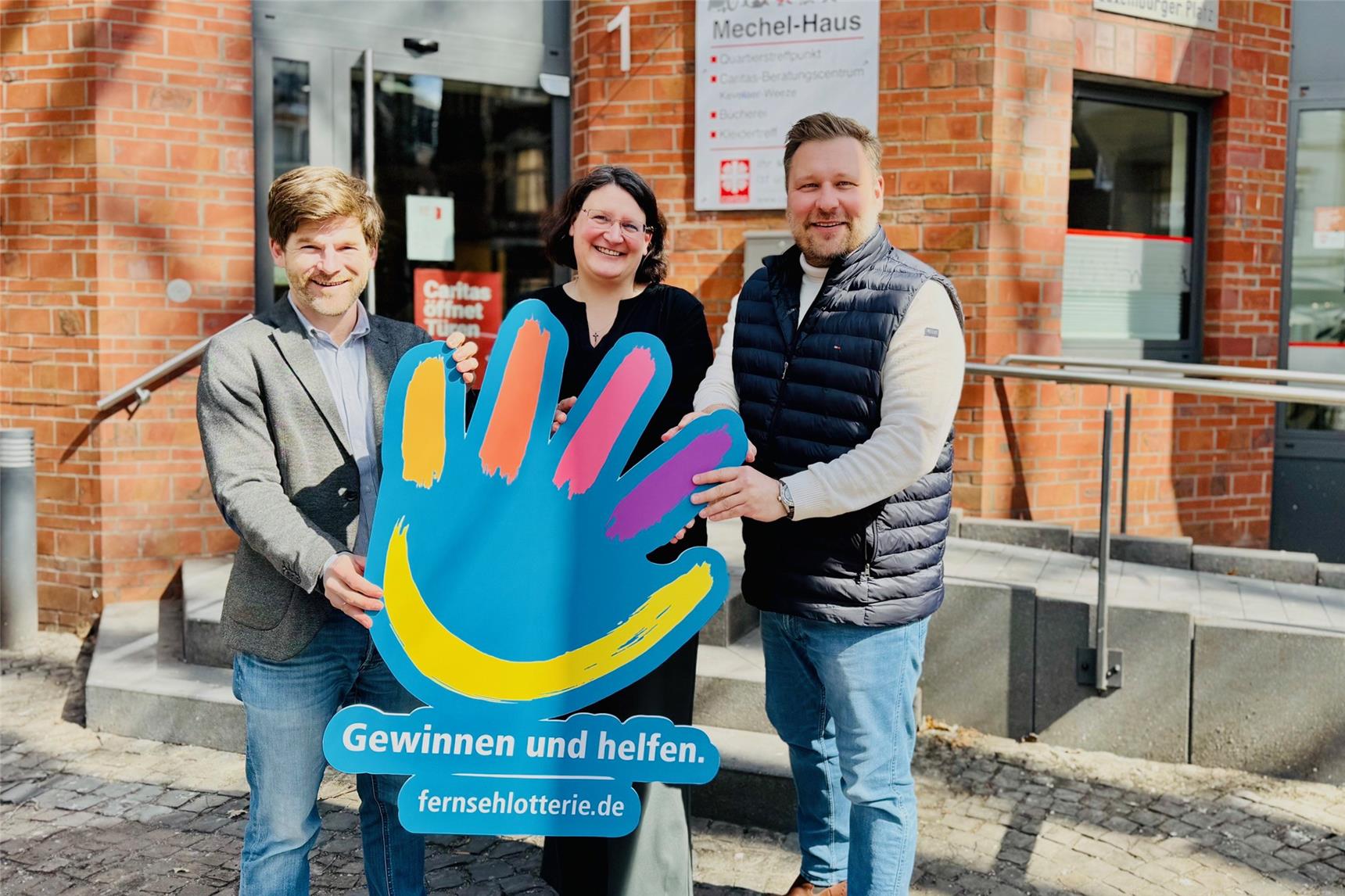 Gerrit Hermans, Jessica Sieben und Stephan Masch stehen mit einem Werbeschild mit der Aufschrift 