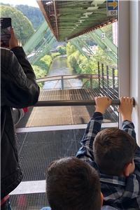 2019_08 Männergruppe Schwebebahn Kinder von hinten blicken aus einem Fenster der Schwebebahn auf die Wupper