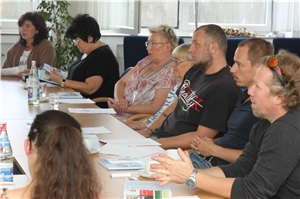 Demenzschulung Plenum Menschen sitzen in einer Reihe an einem Tisch und hören zu