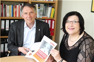 Schutzkonzept Mann und Frau an einem Tisch zeigen Blätter mit Schriftzug und Fotos