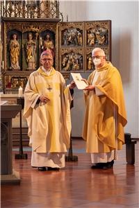Bischof und ein Priester in Messgewändern mit Urkunde