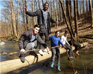 Junge Menschen auf einem Baumstamm über einem kleinen Fluss