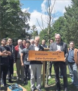 Personen stehen um einen frisch gepflanzten Baum und halten ein Schild "Esskastanie 2018 Galilei Gymnasium"