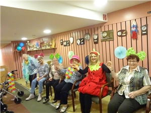 Seniorinnen sitzen bunt kostümiert an der Kegelbahn