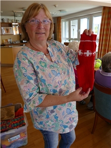 Stricken fürs Jubiläum Mitarbeiterin zeigt rote gestrickte Socken mit eingestricktem weißen Flammkreuz