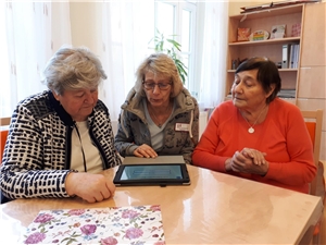 Drei Frauen sitzen am Tisch vor einem Tablet