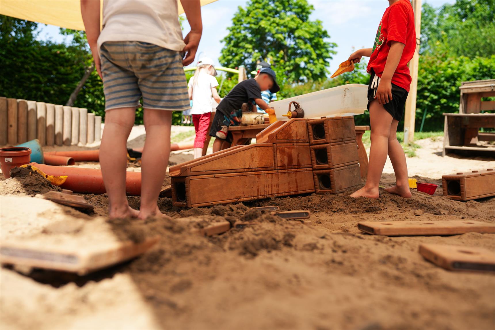 Die Kinder spielen im Sandkasten mit der neuen mobilen Matschanlage.