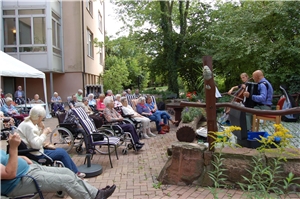 Viele Bewohnerinnen und Bewohner lauschen dem Konzert im Garten