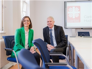 Im Interview: Eugenie Riffel und Ludger Engelhardt-Zühlsdorff zur Zukunft des Caritasverbandes Hochtaunus Im Konferenzraum sitzen Eugenie Riffel (links) und Ludger Engelhardt-Zühlsdorff (rechts) auf den blauen Stühlen, im Hintergrund das Verbandslogo