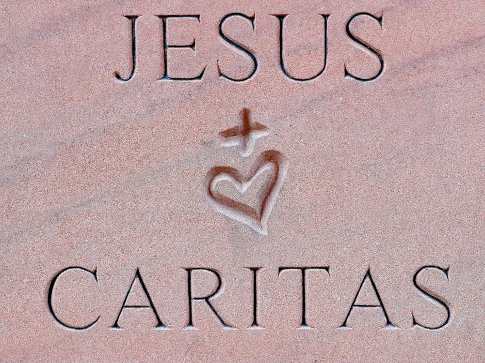 Steintafel mit den Namen Jesus und Caritas, dazwischen ein Herz