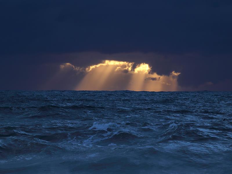 Stürmische See mit dunklen Wolken und Sonnenstrahlen
