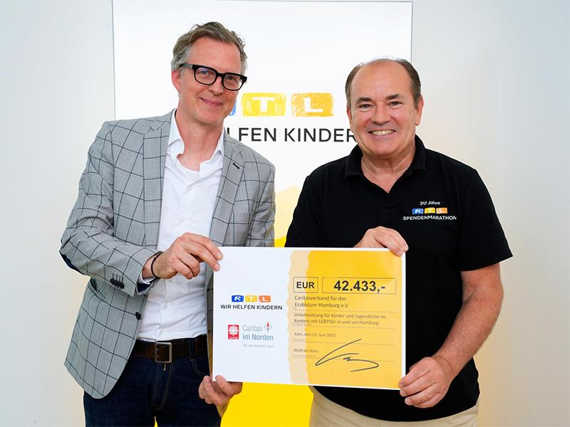 Zwei lächelnde Männer mit einem Spendenscheck