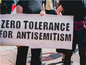 Eine Demonstrantin mit einem Plakat, auf dem steht Zero Tolerance for Anti-Semitism