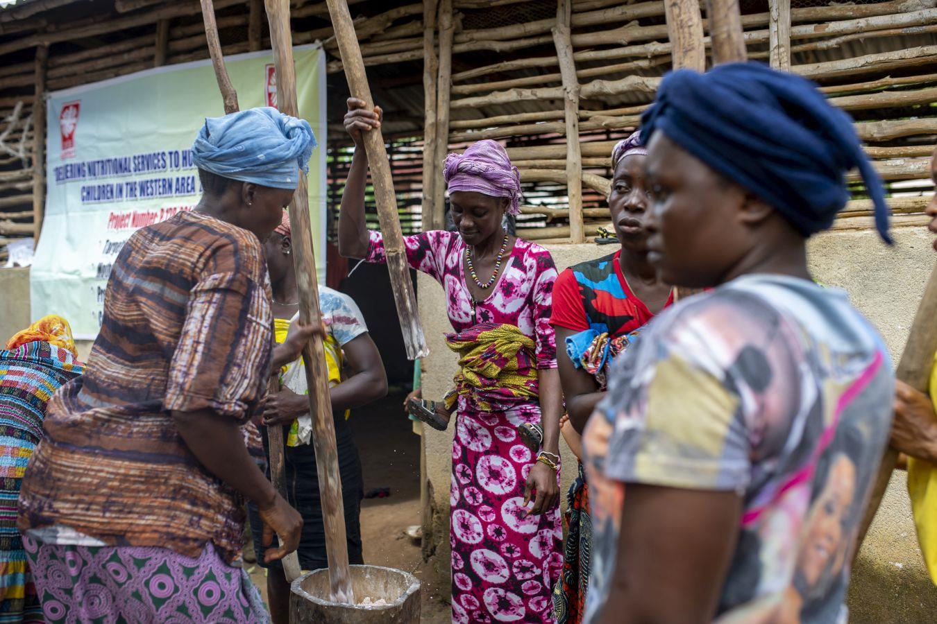 Aminata aus Sierra Leone stellt mit einem Holzstock Spezialnahrung her