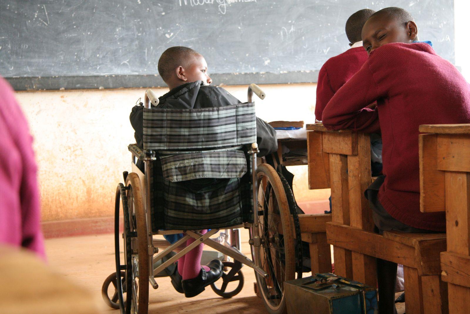 Ein Kind im Rollstuhl sitzt neben den anderen Schülern in einer Reihe