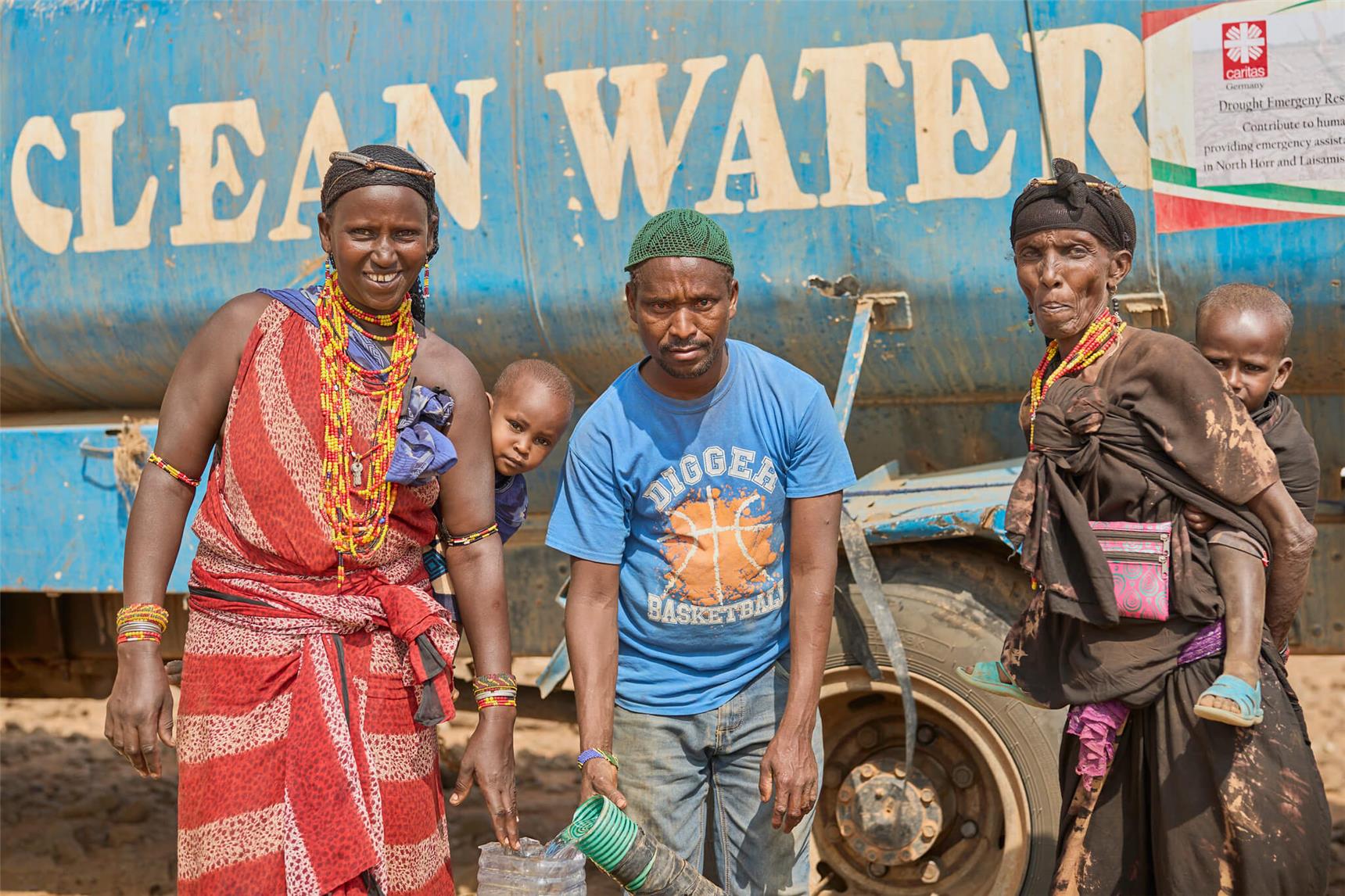 Drei Personen holen frisches Wasser vom Tanklaster in Kenia, Marsabit.