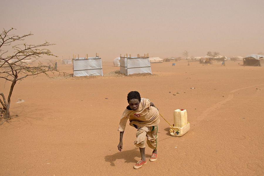 Junge zieht Wasserkanister an einem Seil durch ein Camp