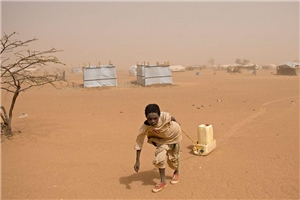 Junge zieht Wasserkanister an einem Seil durch ein Camp