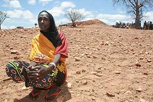 Frau sitzt in einer ausgetrockneten Landschaft