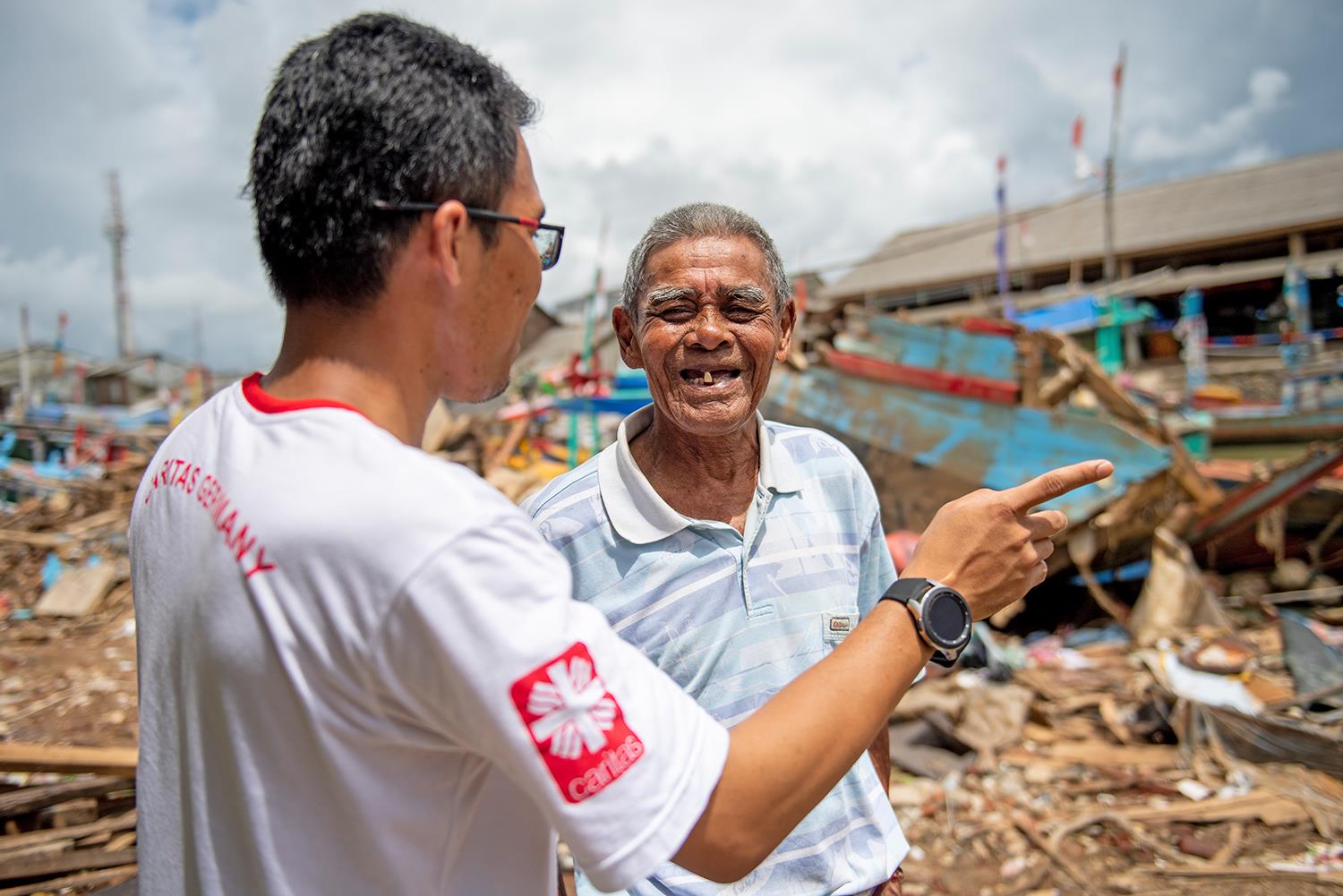 Ein Caritas-Mitarbeiter spricht mit einem ehemaligen Fischer, dessen Hütte durch den Tsunami zerstört wurde.