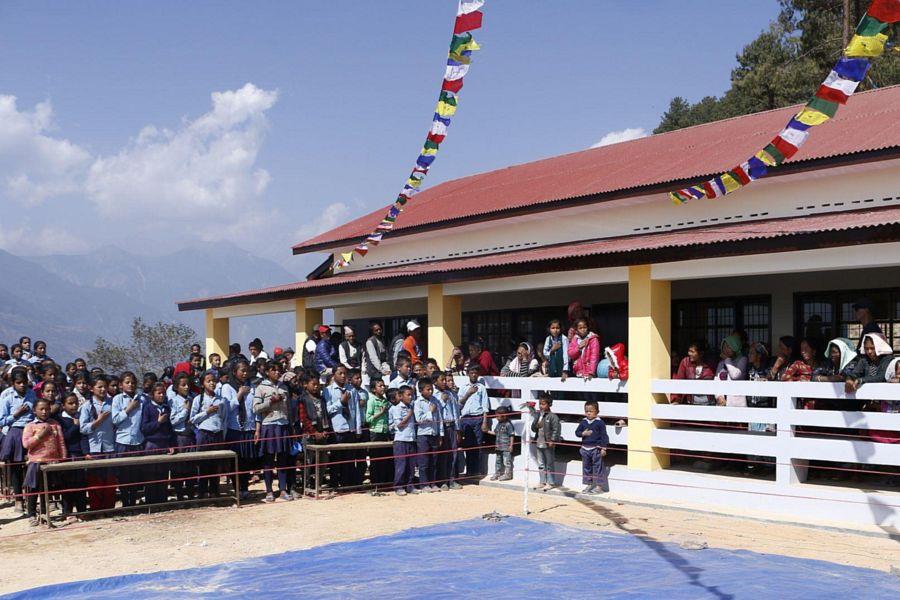 Kinder und Erwachsene während einer Zeremonie vor dem neuen Schulgebäude.
