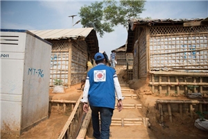 Rohingya Rückansicht eines Caritas-Mitarbeiters der an Hütten vorbeiläuft