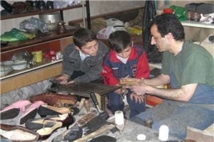 Schuster zeigt Kindern sein Handwerk
