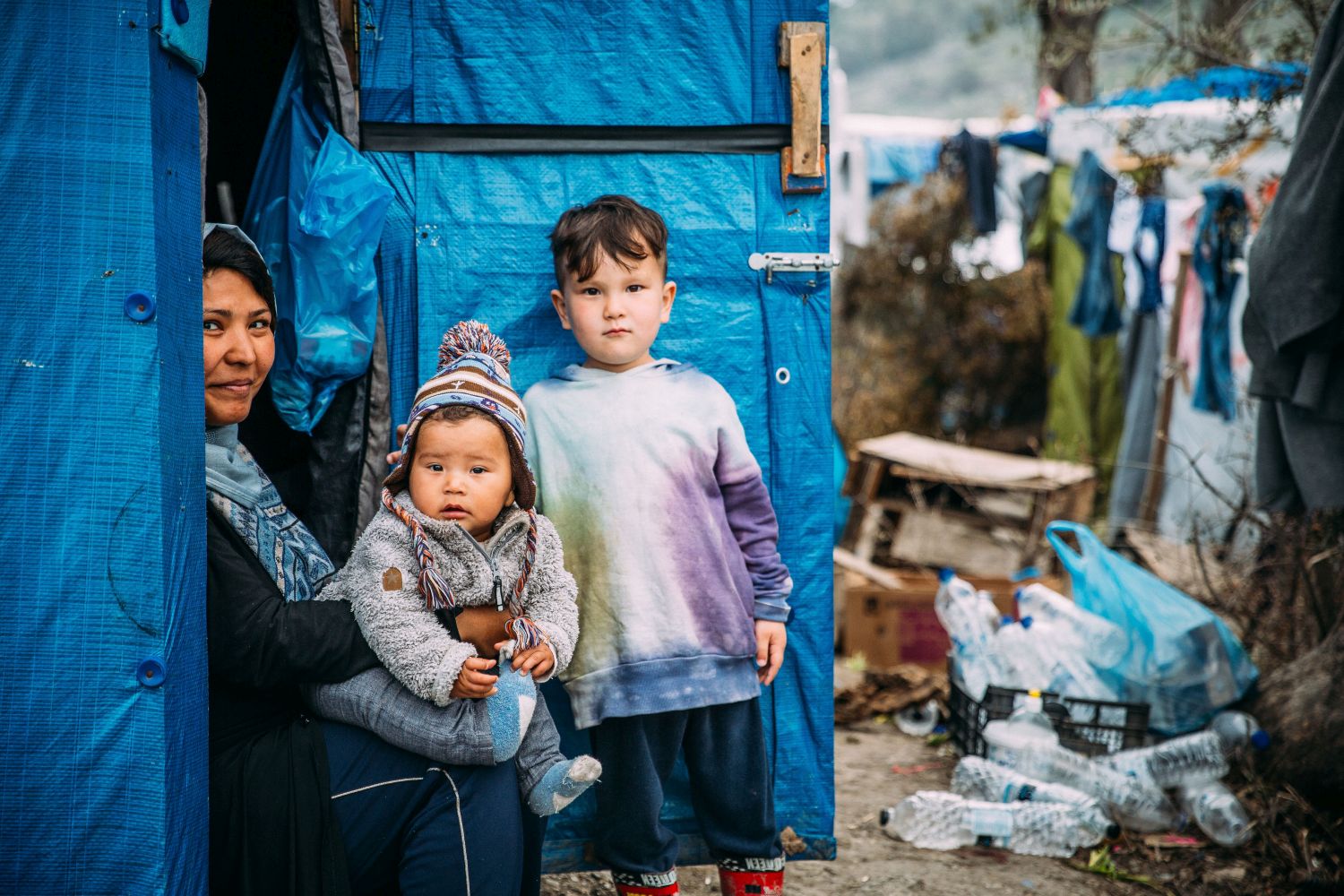 Zwei Kinder und eine Frau sitzen in einem Flüchtlingszelt auf Lesbos