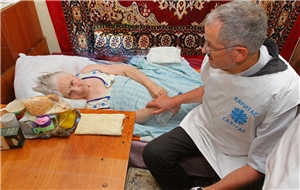 Caritas-Präsident Neher am Bett einer alten Frau