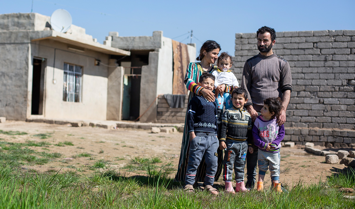 Jesidische Familie vor ihrem Haus im kurdischen Dorf Sershka