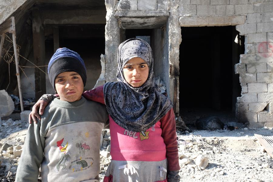2 Kinder (Schwester und Bruder) vor zerbombten Häusern