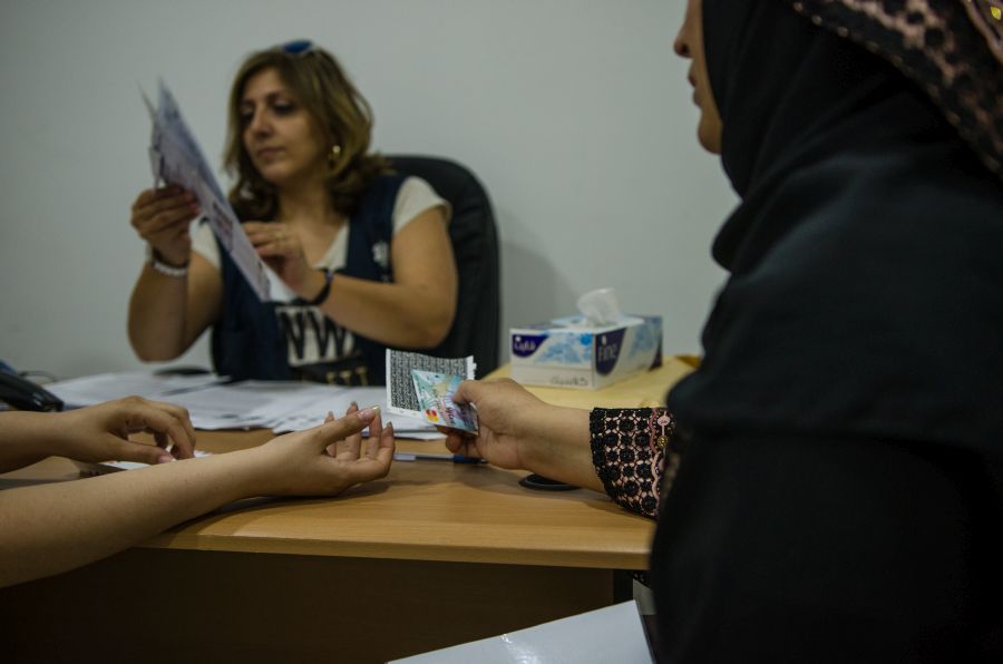 Frau erhält geldkarte für Bargeldhilfen im Caritas Sozialzentrum Irbid in Jordanien
