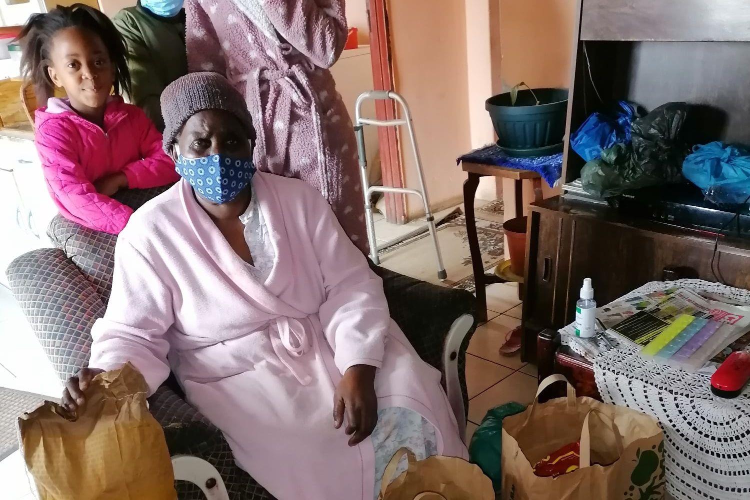 Eine Seniorin erhält ein Nahrungsmittelpaket für sich und ihre Familie.