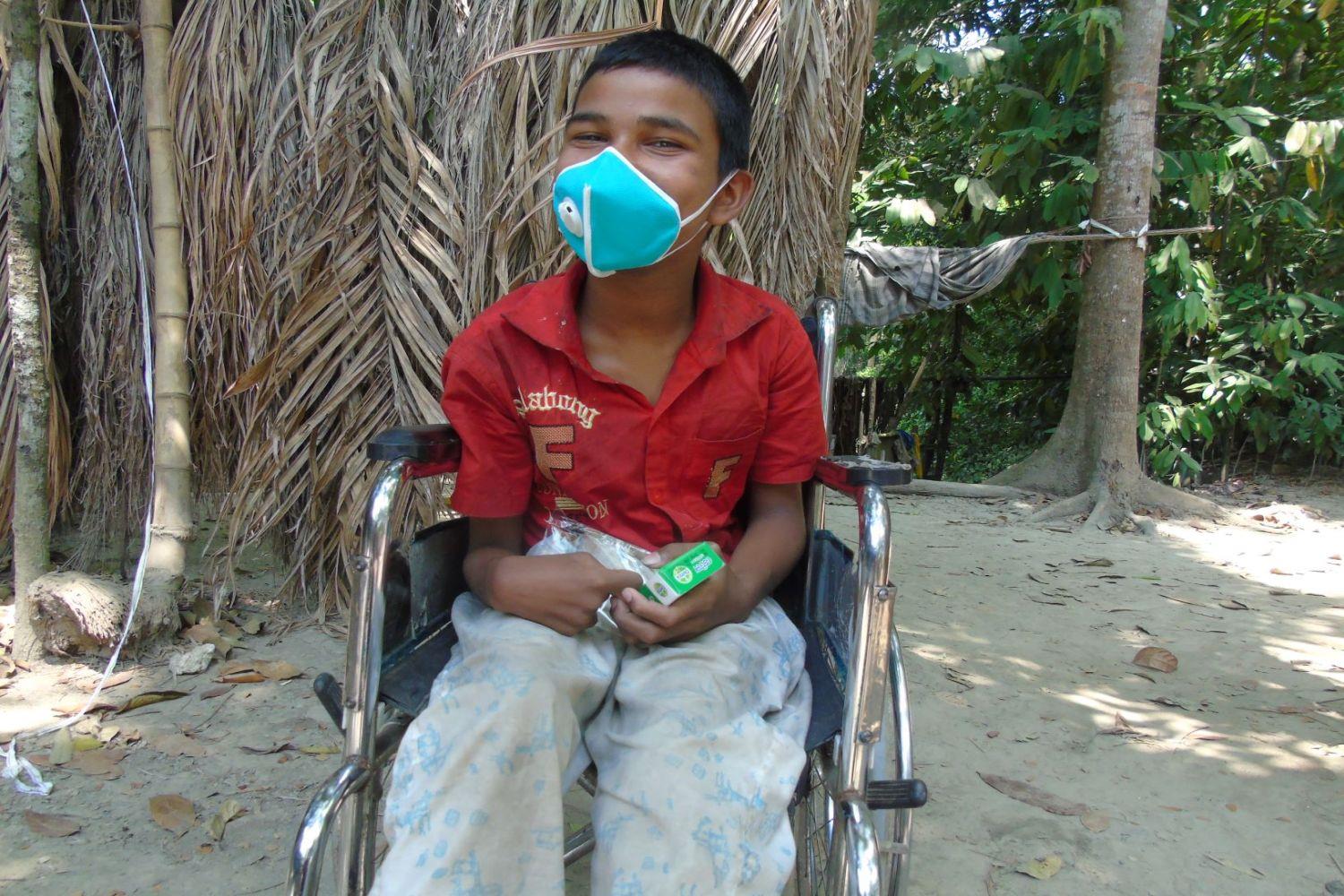 Ein Junge im Rollstuhl mit Maske und einem Hygienekit.
