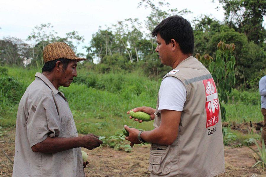 Ein Kleinbauer im Gespräch mit einem Caritas-Mitarbeitenden.