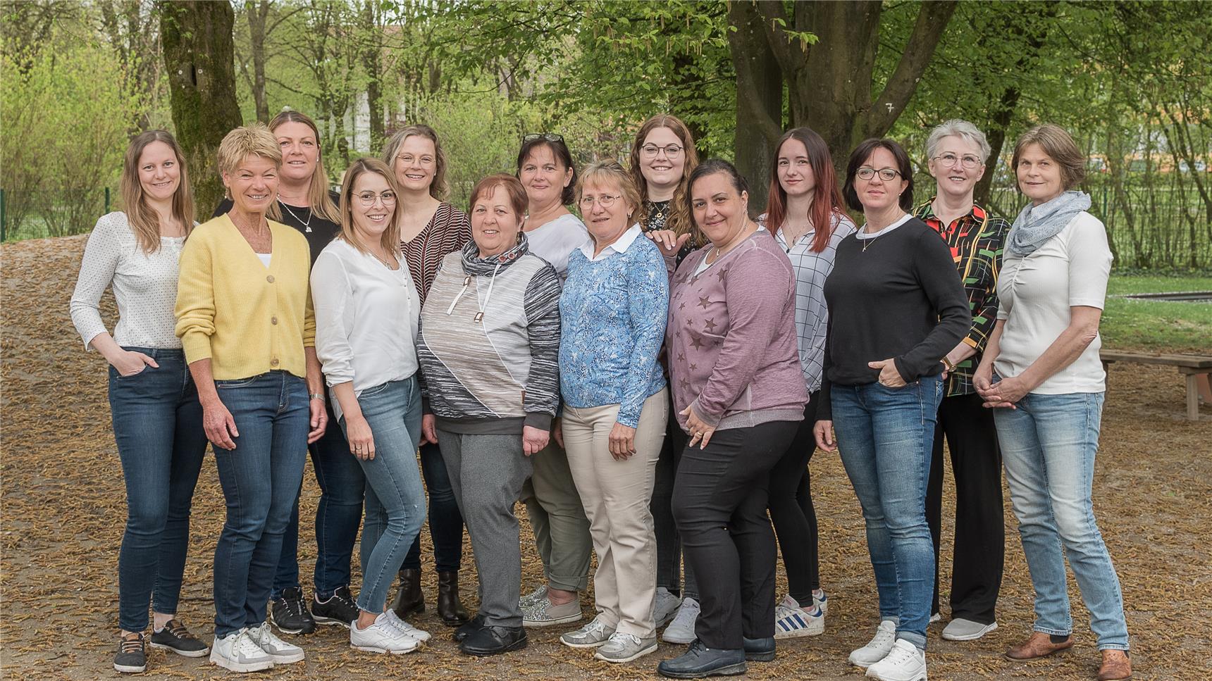 Eine Gruppe von Frauen steht zusammen vor Bäumen und lächelt in die Kamera.