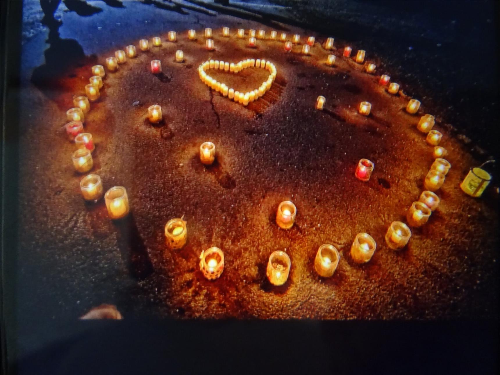 Kerzen um ein Herz auf dem Boden angeordnet, symbolisieren Liebe und Zuneigung in einer stimmungsvollen Umgebung.