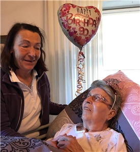 Pflegekraft gratuliert Patientin zum 90. Geburtstag