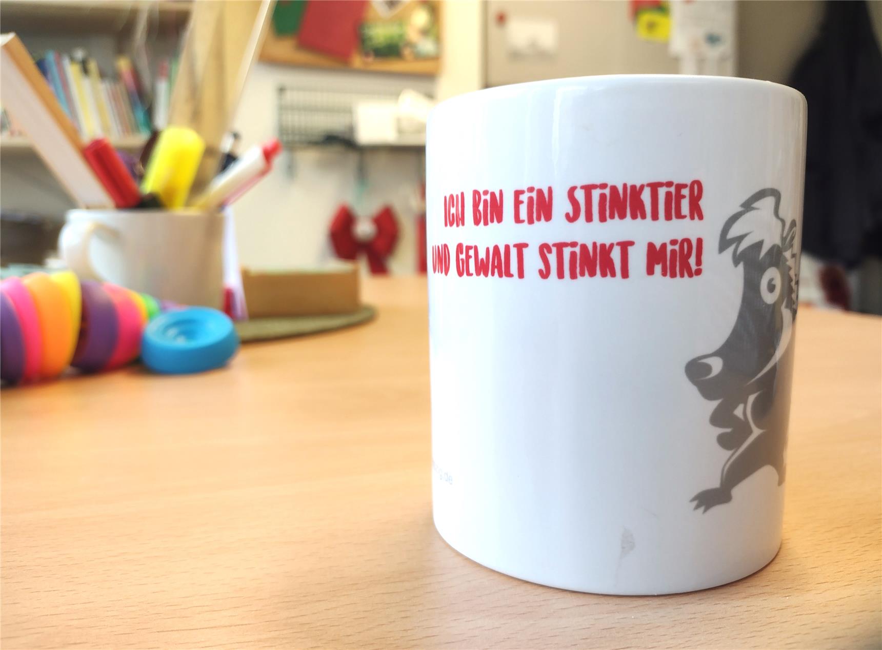 Auf einem Tisch im Klassenraum steht eine Tasse mit dem Schriftzug: Ich bin ein Stinktier und Gewalt stinkt mir
