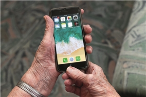 Hand eines älteren Mannes hält ein Smartphone