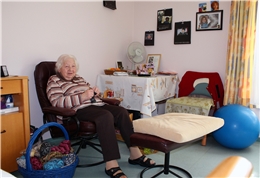Bild einer strickenden Seniorin in ihrem Zimmer