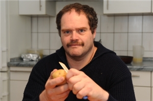Mann schält Kartoffel in einer Küche