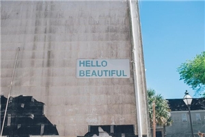 Auf einer grauen, dreckigen Hauswand steht in großen türkisen Buchstaben der englische Text "Hello beautiful"