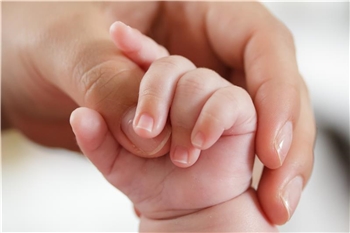 Eine Mutterhand hält eine Babyhand