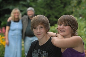 Erziehungsberatung1 Ein Mädchen und ein Junge sind im Vordergrund, ihre Eltern stehen im Hintergrund