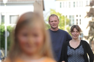 Erziehungsberatung2 Ein Elternpaar steht im Hintergrund, vorne ist unscharf ihre Tochter zu sehen.
