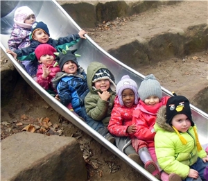 Kindergartenkinder auf einer Spielplatz-Rutsche