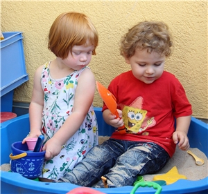 Mehrere Kinder sitzen an einem Tisch, auf dem Schüsseln mit Nudeln und Tomatensoße stehen.